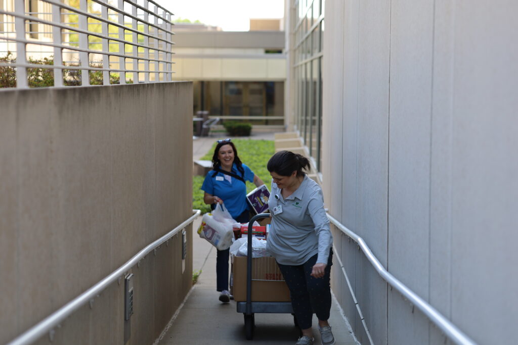 Two women transporting items on cart