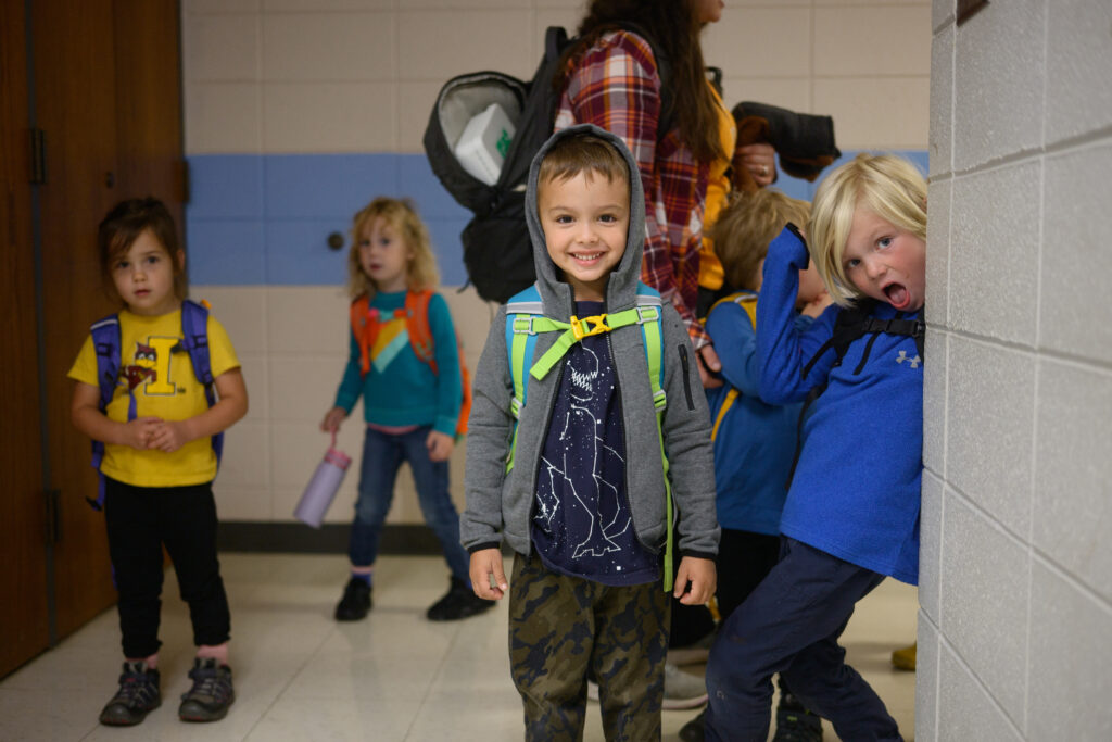 Children in a school hallway smiling