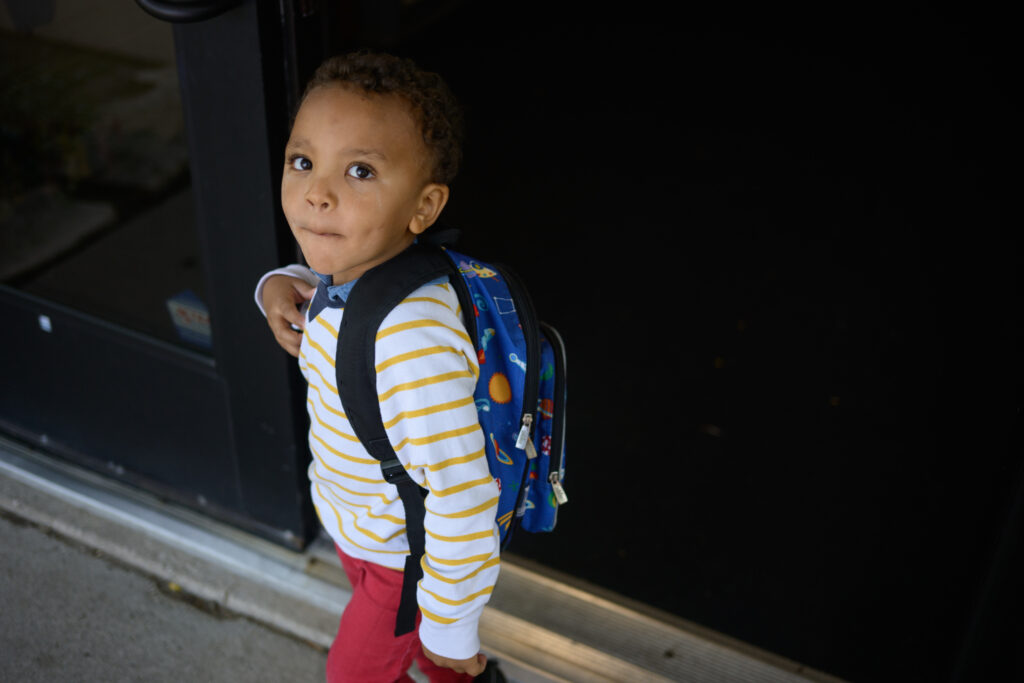 Child with backpack at doorway