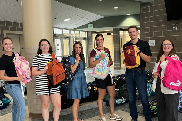 Group holding colorful backpacks indoors